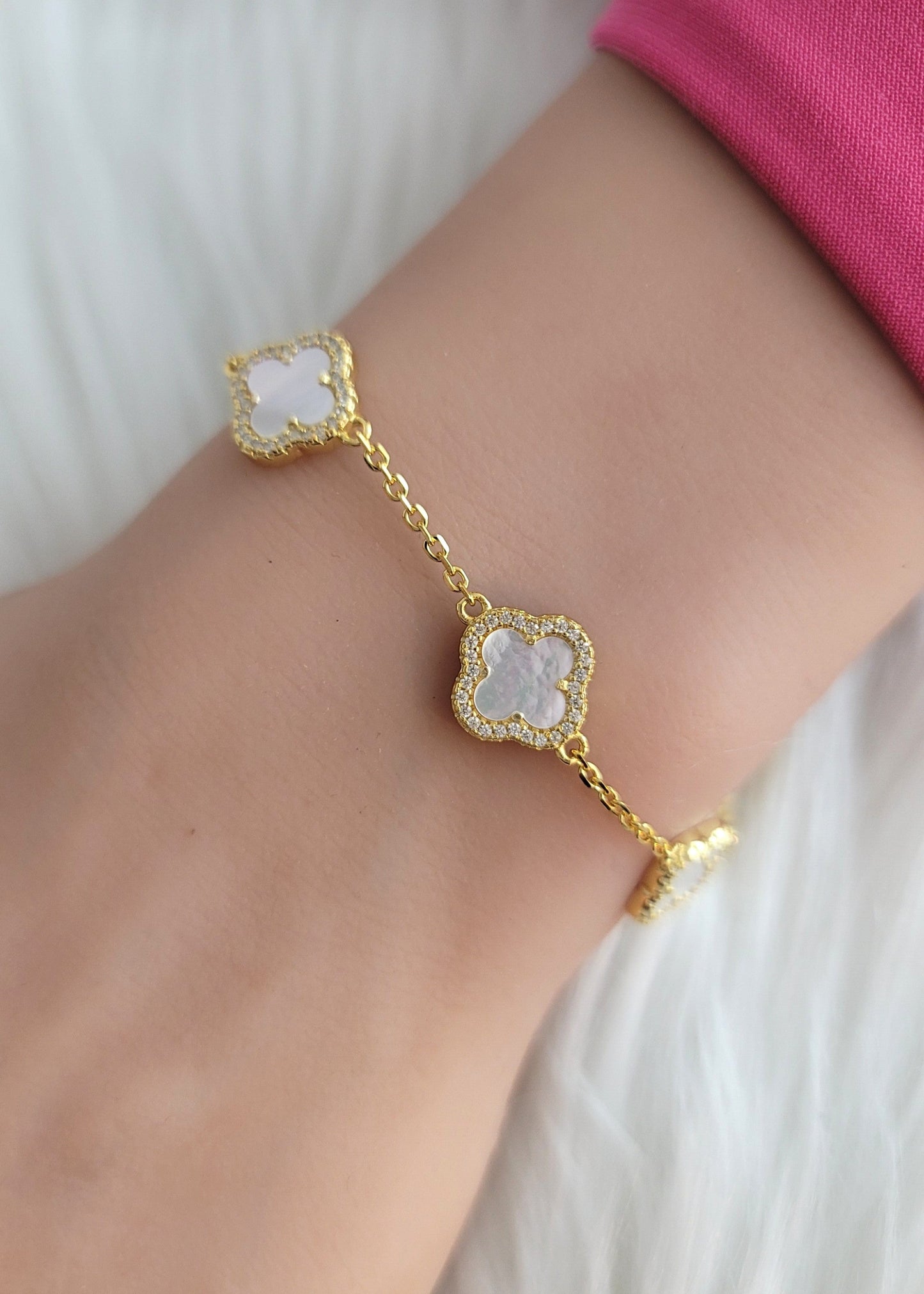 Gold bracelet with a white stone on a wrist against a white background